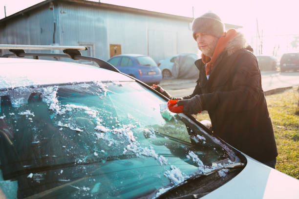 istock Man scraping ice from car on winter morning 1364927668