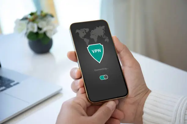 Photo of male hand holding phone with app vpn on the screen