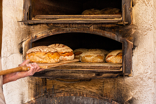 Baking bread in an old time stone woodfired oven, traditional austrian street stove.