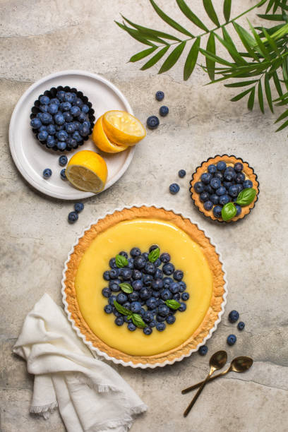 istock Summer table with blueberry and lemon curd tart on grey stone table. Top view. Vertical image. Copy space. 1364931570