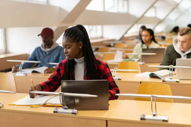 Photo of Young afro-American student is writing in the library