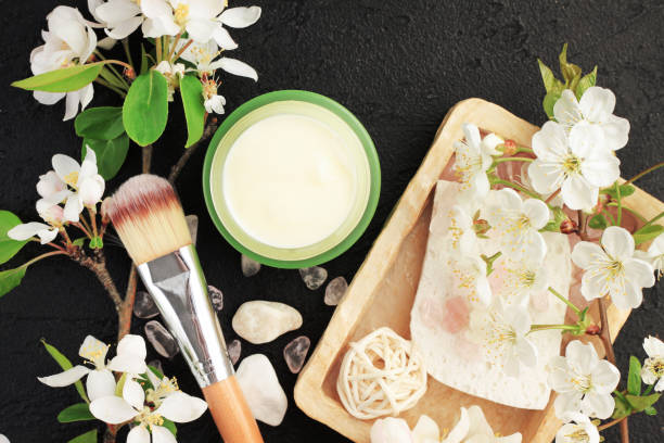 Botanical spa treatment herbal cosmetic products top view black table background, facial moisturizer container, fresh flower fresh white flower blossom, soap bar,skin care and beauty therapy botanical spa treatment stock pictures, royalty-free photos & images