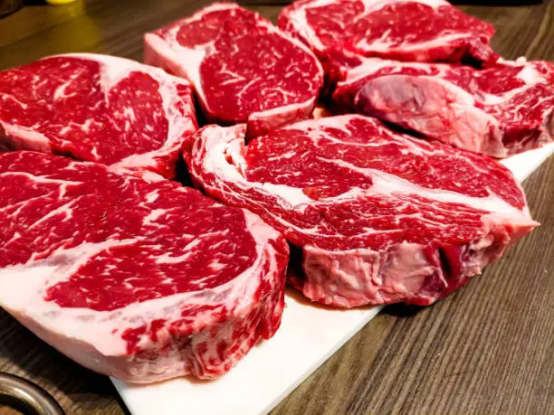 A marbled beef rib eye steak is waiting to be grilled.