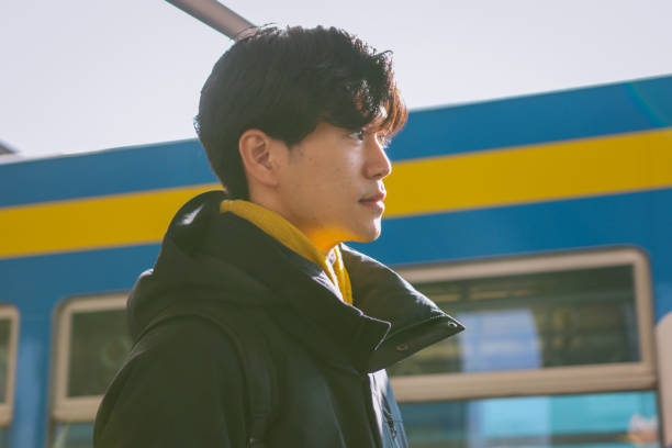 Asian Young man holding a phone is waiting for public transportation to arrive.
