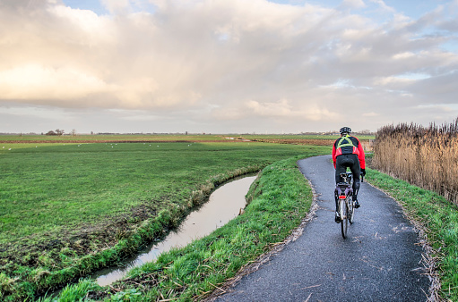 Schoonhoven, The Netherlands. January 9, 2022: a speed cyclist on a curving asphalt path through the Krimpenerwaard polder