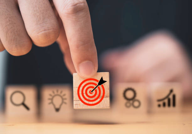 istock Hand  putting target board which printing on wooden cube block on mechanical gear and lightbulb icon  for creative and set up business objective target  goal concept. 1364940016