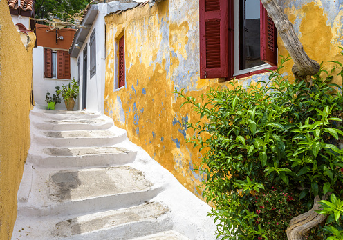 Street in Plaka district, Athens, Greece, Europe. Cozy lanes with old houses are tourist attraction of Athens. Scenic narrow alley with steps and plants at Acropolis slope in Athens city center.