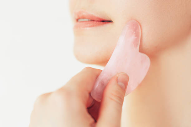 istock The girl drives stone massager over her cheekbones 1364943996