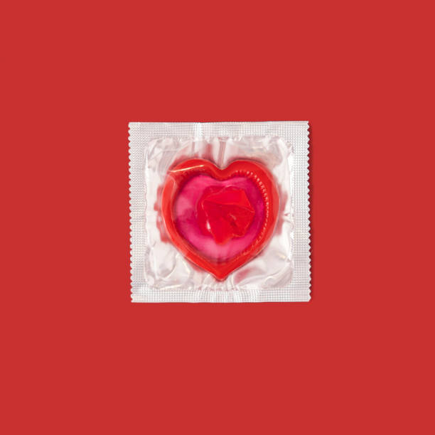 In the package, red condom in the shape of heart on red background stock photo