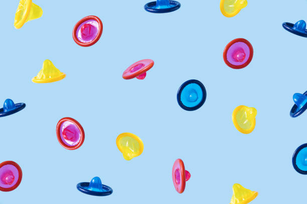 Falling multi-colored condoms on blue background stock photo