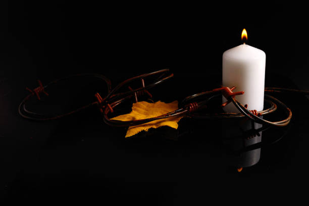 istock Holocaust memory day. Arbed wire and burning candle on black background 1364945132