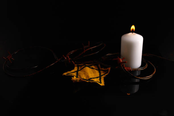 istock Holocaust memory day. Arbed wire and burning candle on black background 1364945662