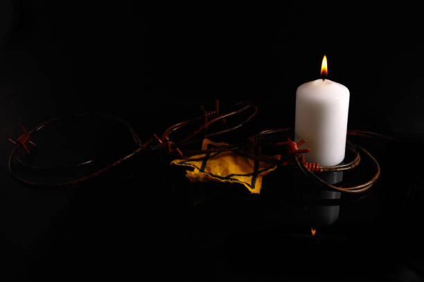 istock Holocaust memory day. Arbed wire and burning candle on black background 1364946161
