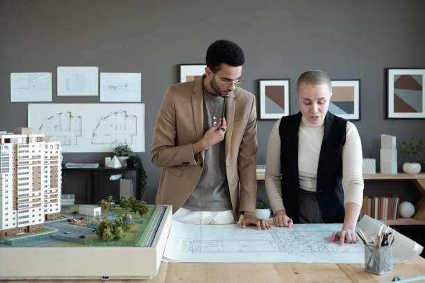 istock Two elegant architects or engineers discussing sketch on blueprint 1364947209