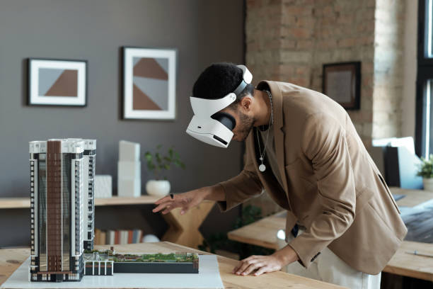 istock Young architect in vr headset bending over house layout 1364947229