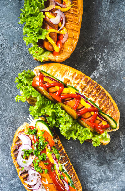 istock Grilled Hot Dogs with different toppings on the kitchen table. Vertical background. 1364951957