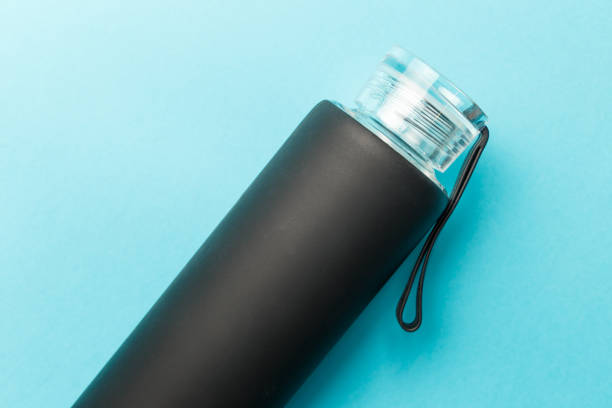 istock Stylish reusable eco-friendly glass bottle with a black rubberized surface on a blue background. Space for text. Top view. Flat lay. The concept of a lifestyle without plastic and waste 1364956745