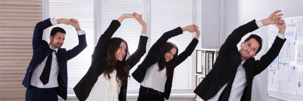 istock Businesspeople Doing Exercise Behind Desk 1364959130