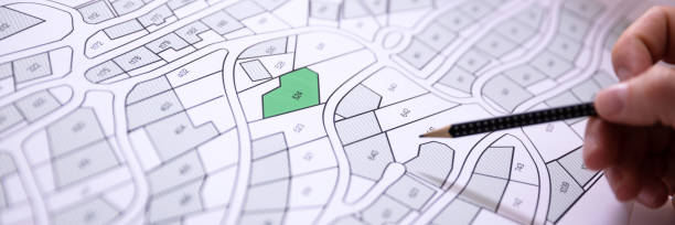 istock Human Hand Holding Pencil Over Cadastre Map 1364959145