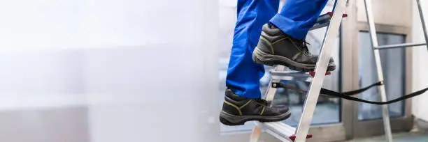 Low Section View Of A Handyman's Foot Climbing Ladder