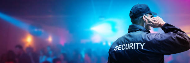 Security Guard Listening To Earpiece Against Building