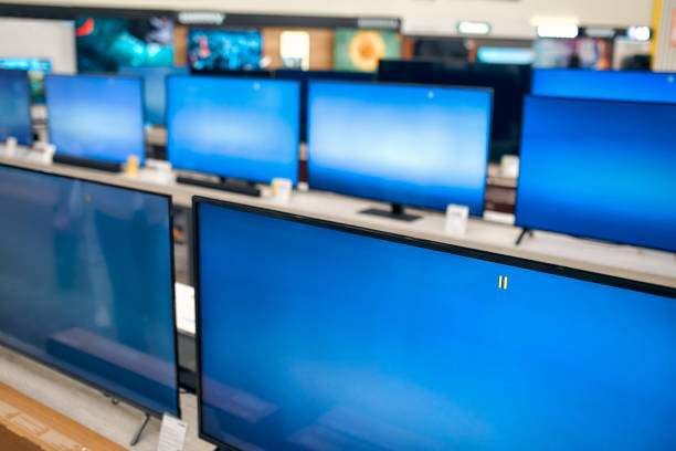 Showcase with plasma TVs with blue screen in store of household appliances, electronics and gadgets. Buying new TV, sale day.