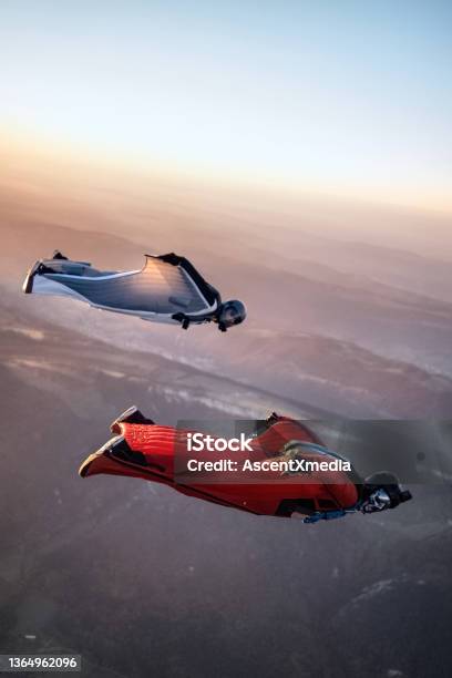 Wingsuit Fliers Soar Above Swiss Mountain Landscape Stock Photo - Download Image Now