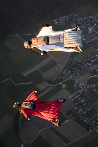 les aviateurs wingsuit s’élèvent au-dessus du paysage de montagne suisse - wingsuit photos et images de collection