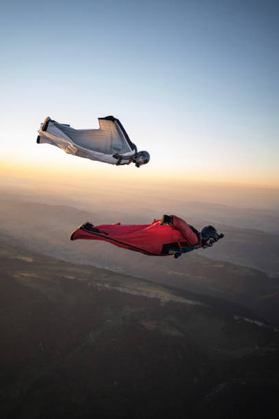 les aviateurs wingsuit s’élèvent au-dessus du paysage de montagne suisse - wingsuit photos et images de collection