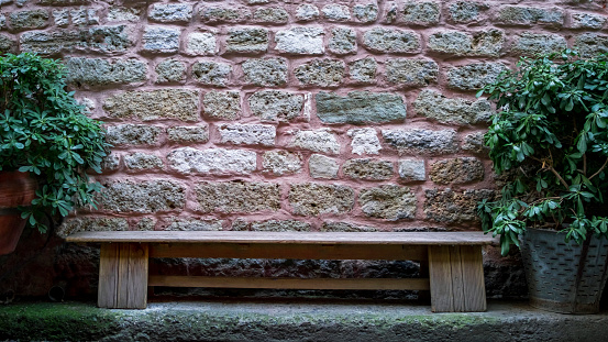 wooden bench in front of stone wall