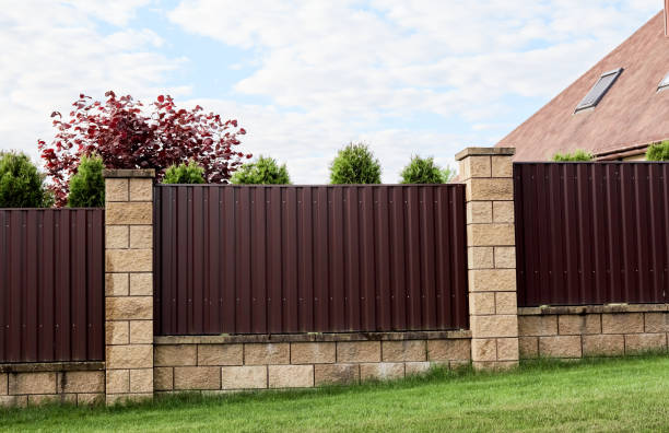 istock Brown metal profile fence with block posts. Incline construction. Corrugated surface. Security. Private property fencing. Opaque hedge. Outdoor house exterior. Side view. Urban or industrial style 1364963083
