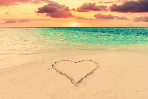 istock Heart on sand on tropical beach at sunset. 1364970124