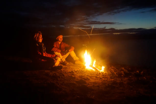 Olkhon Island, Russia - September 7, 2020: Travelers warm themselves by the fire at night
