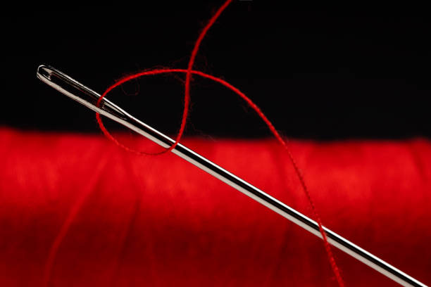 A detailed macro shot of a needle piercing through a spool of white thread, symbolizing precision, craftsmanship, and the art of sewing. The minimalist composition emphasizes the texture of the thread and the sharpness of the needle, making it ideal for themes related to tailoring, fashion, textiles, and handmade creativity.