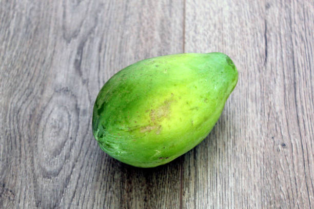 istock Unripe papaya fruit isolated on wood background 1364976746