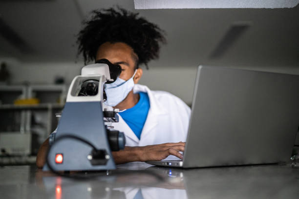 대학에서 노트북을 사용하여 실험실에서 공부하는 젊은 남자 - 얼굴 마스크를 사용하여 - 생물 수업 뉴스 사진 이미지