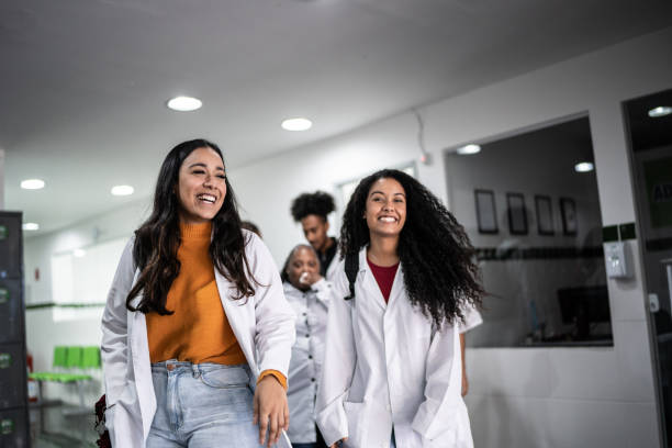 enseignant et élèves marchant dans le couloir de l’école ou de l’université - healthcare and medicine smiling group of people lab coat photos et images de collection