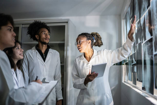 teacher holding a digital tablet and explaining about xrays to students - x ray image radiologist examining using voice imagens e fotografias de stock