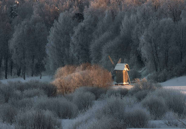 Winter beautiful fairy tale. An old wooden mill in a field under the snow near the river soaring in the frost on the background of the forest in the Pushkin mountains, Pskov Winter beautiful fairy tale. An old wooden mill in a field under the snow near the river soaring in the frost on the background of the forest pskov city stock pictures, royalty-free photos & images