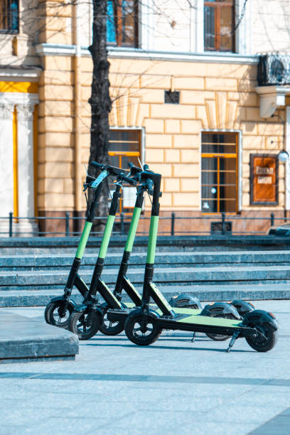 rental electric kick scooter parked at city street rental electric kick scooter parked at city street copy space lime scooter stock pictures, royalty-free photos & images