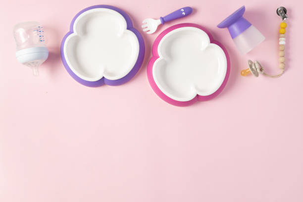 istock Flat lay set of plastic dishware, feeding bottles and pacifier on pink background with copy space top view 1364986125