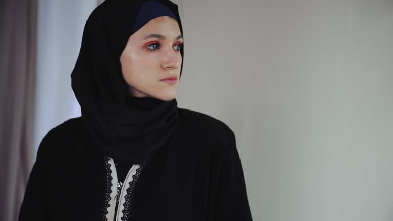 Thoughtful muslim woman in traditional arabian abaya dress on gray background