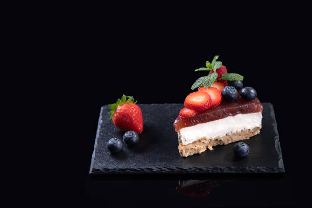 istock Piece of cheesecake served on slate plate isolated on black background with copyspace. Homemade bakery concept. 1364988717