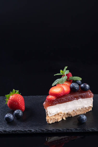 istock Piece of cheesecake served on slate plate isolated on black background with copyspace. Vertical format. Homemade bakery concept. 1364988736