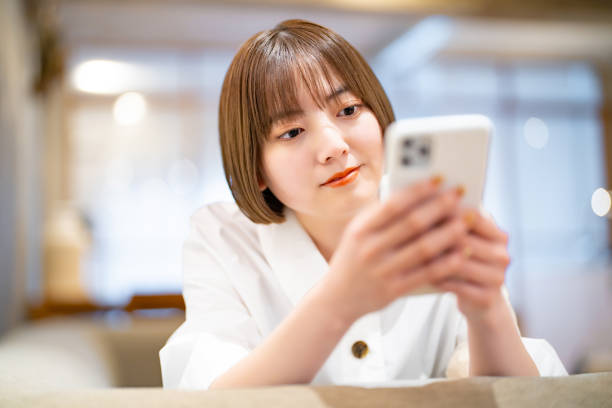 スマートフォンを操作している女性 - 女子大生 ストックフォトと画像