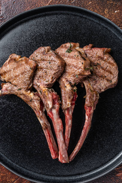 istock BBQ Grilled lamb chops steaks in a plate. Dark background. Top view 1364989199