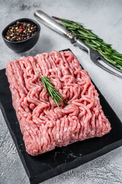 istock Minced chicken or turkey raw meat on cutting board with herbs. White background. Top View 1364990439
