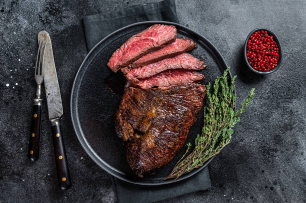 Grilled hanger or Onglet beef meat steak on a plate with thyme. Black background. Top View Grilled hanger or Onglet beef meat steak on a plate with thyme. Black background. Top View. roast beef photos stock pictures, royalty-free photos & images