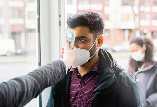 istock Man going through body temperature checkpoint at office entrance 1364991887