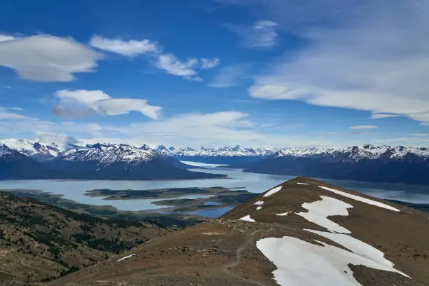 Blue ice of Perito Moreno Glacier in Glaciers national park in Patagonia, Argentina from far away, view from top of a mountain, with Lago Roca in the foreground and snow covered mountains of the Andes in the distance